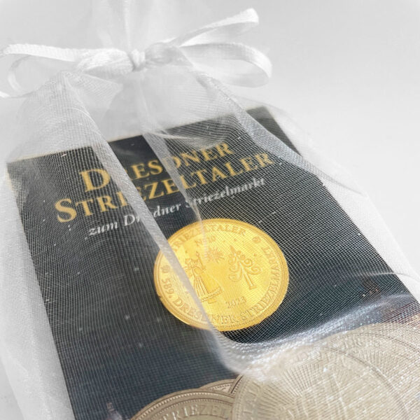 Geschenksäckchen aus cremefarbenem Organza mit 10 gemischten silberfarbenen Striezeltalern und einem goldfarbenen Taler mit dem Motiv 2023.